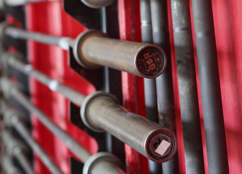 Row of barbells stored on a red rack at DEUCE Gym