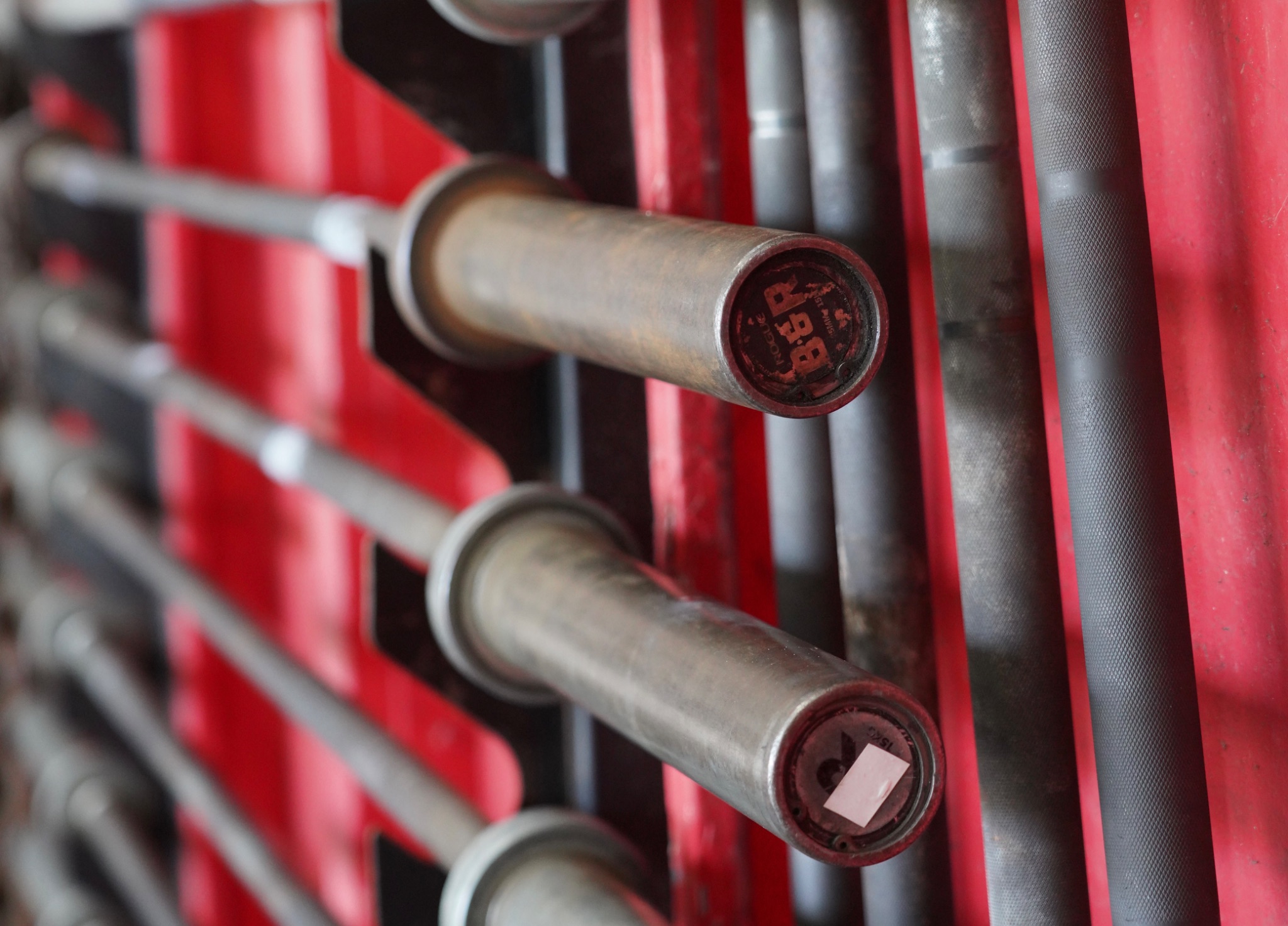 Row of barbells stored on a red rack at DEUCE Gym