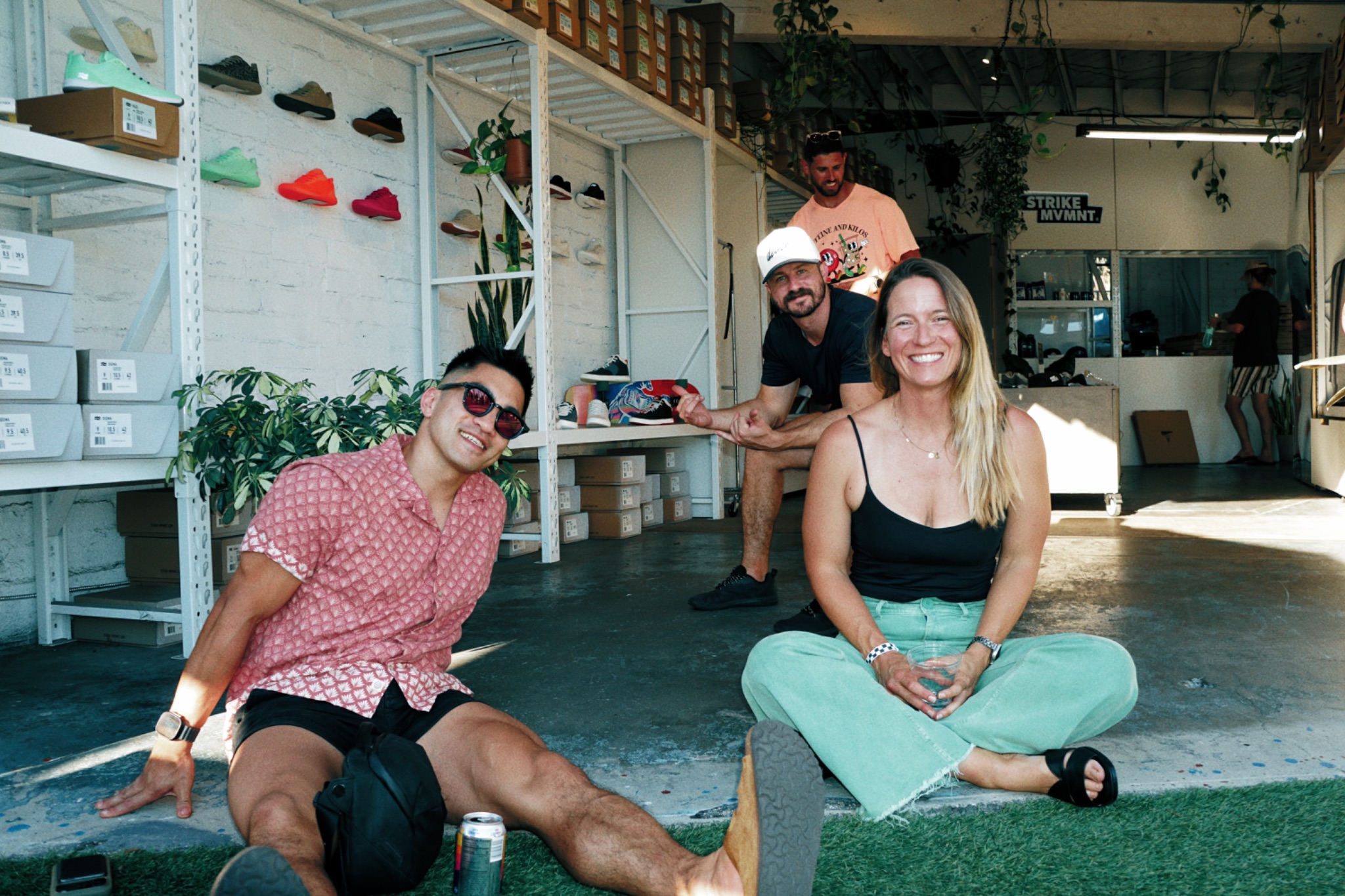 DEUCE Gym members smiling on the turf in front of the STRIKE MVMNT shoe wall at DEUCE Gym
